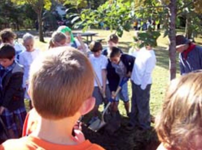 Children celebrating Arbor Day by planting a tree.