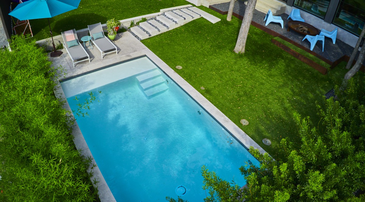 Concrete pool and walkway surrounded by green