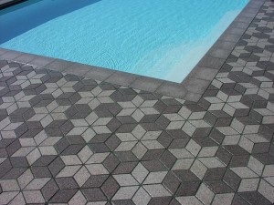 Concrete pavers used for pool decking installed in a six-pointed star pattern using light and dark grey pavers.