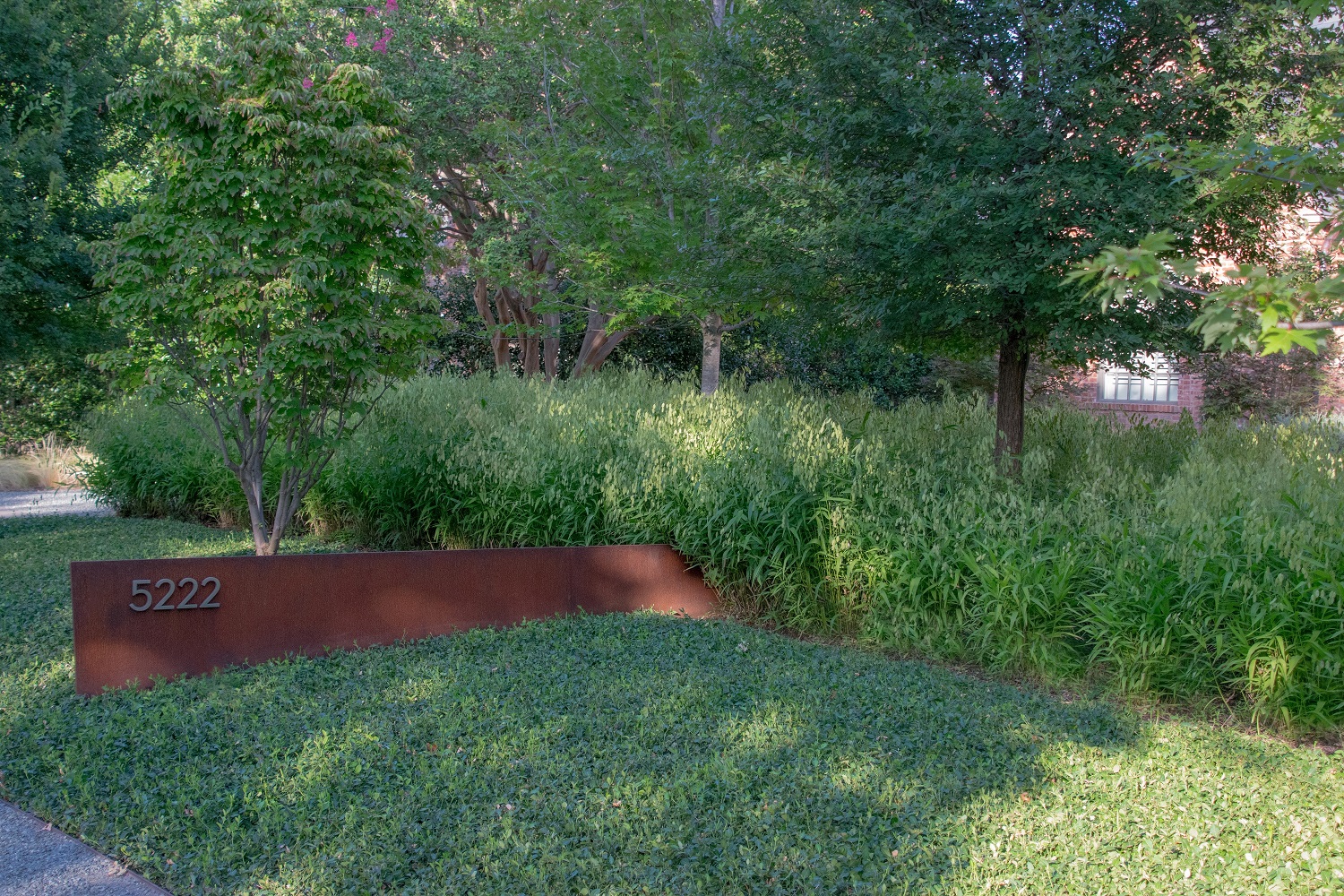 Landscape design detail features modern address sign.