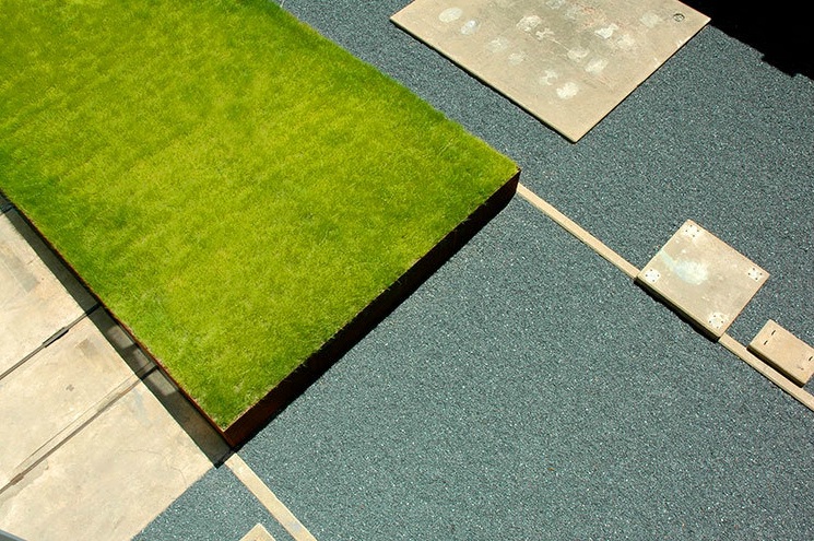 Birds eye view of contemprary residential lawn with grid-like design featuring black basalt gravel, large cement pavers and grass.