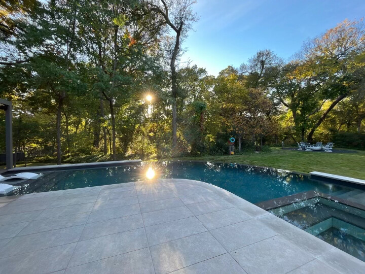 Terrace of Italian porcelain pavers overlooking negative edge pool at sunset