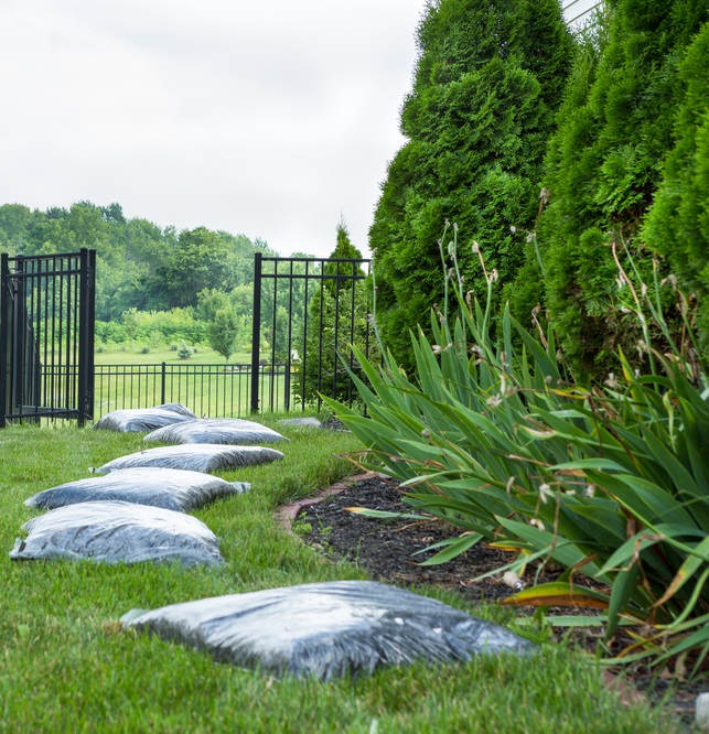 Yard with bags of mulch lying next to flower bed.