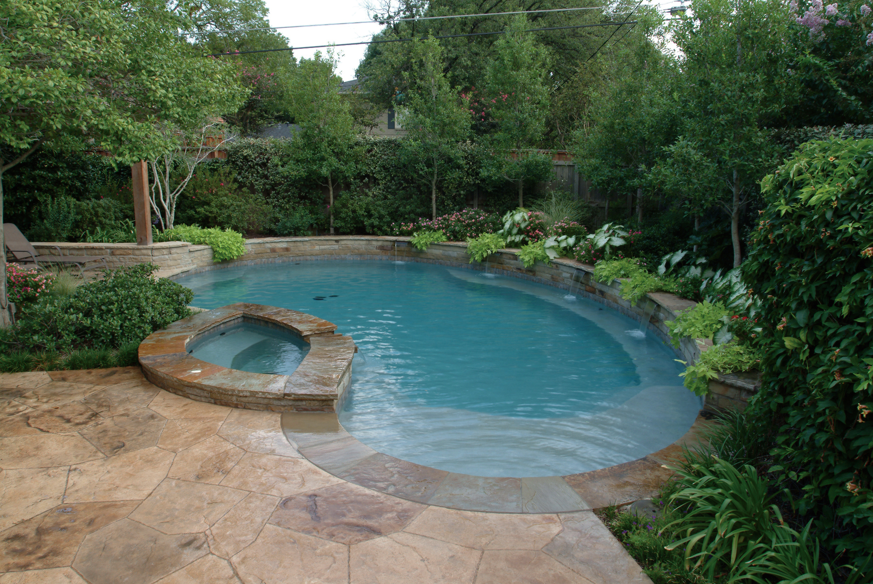 Overhead view of a pool and spa with a custom designed stamped concrete or textured concrete deck in Dallas, Texas.