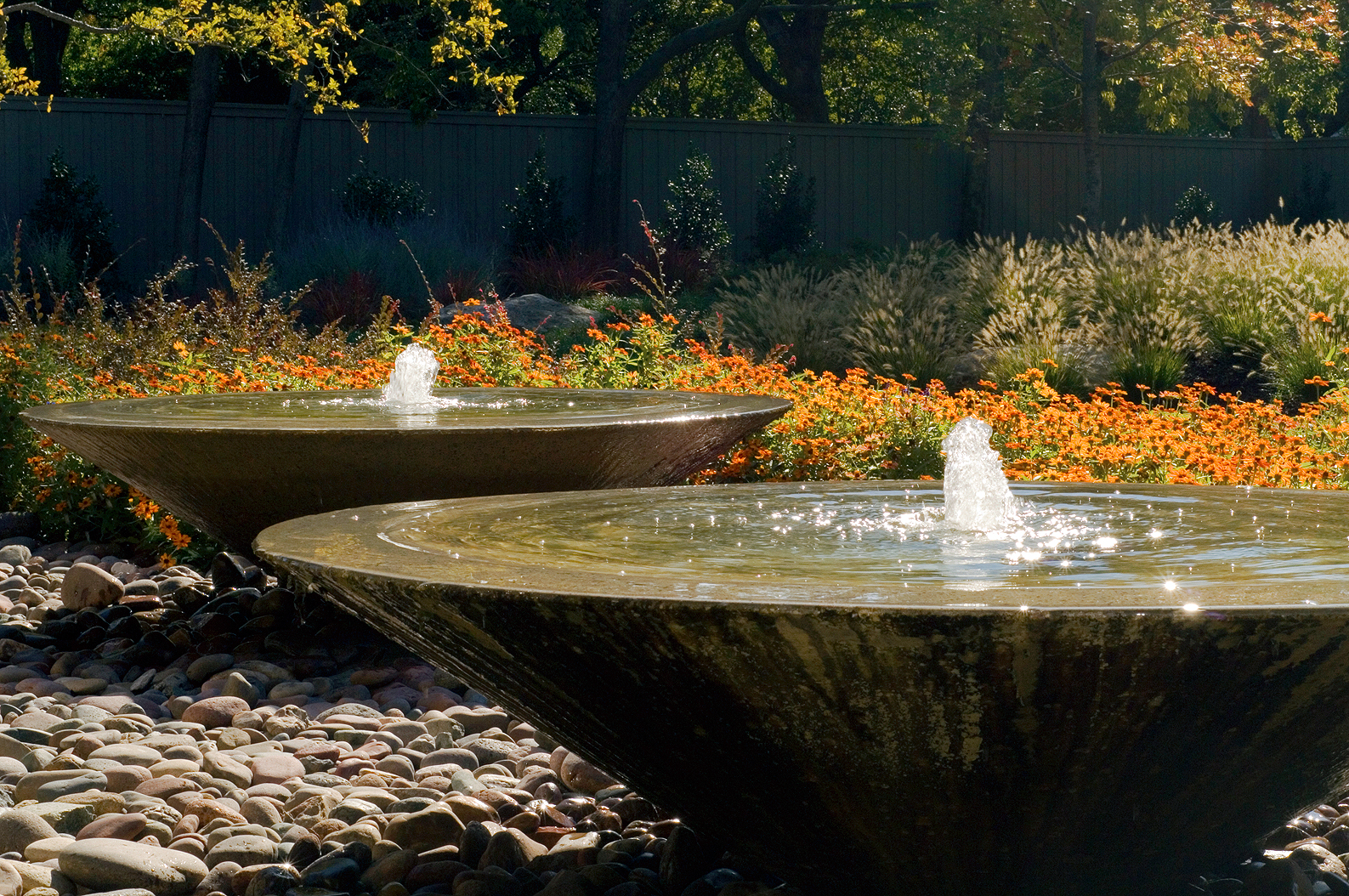 Three low-profile poured cement fountains in a bed of New Mexican River Rock are a focal point of this contemporary residential landscape in Dallas, Texas.