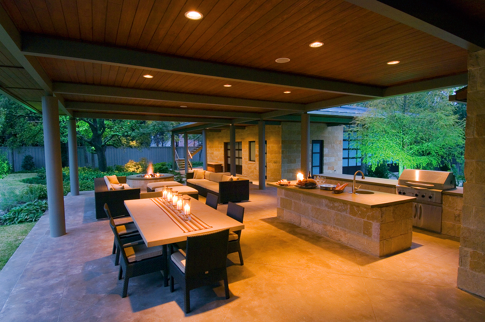 Outdoor kitchen with poured concrete floor and wood ceiling designed by Bonick Landscaping of Dallas, Texas.