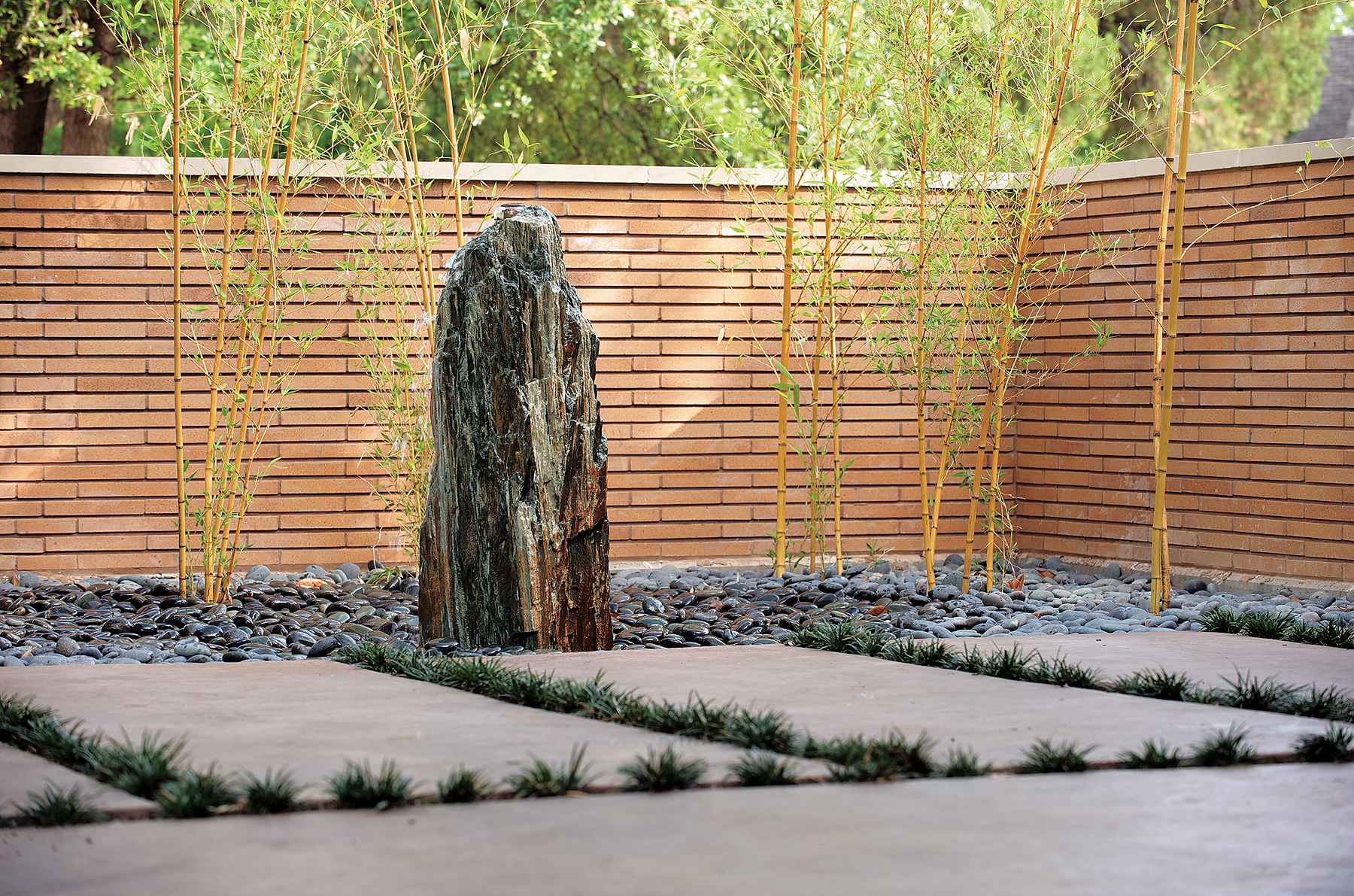 Contemporary residential landscape features natural rock fountain in a bed of Mexican beach pebble gravel.